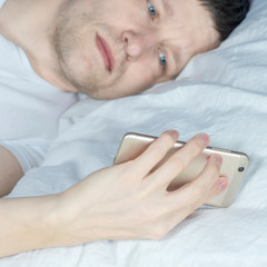 man sleeping at night in bed while using smartphone for chatting, flirting and sending text message in internet addiction and mobile abuse concept