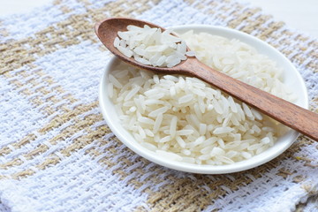 Natural raw white rice grains, on display in bowl and wooden spoon