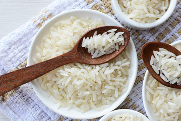 Natural raw white rice grains, on display in bowl and wooden spoon
