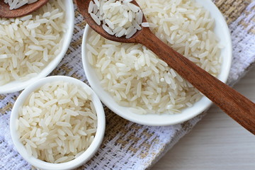 Natural raw white rice grains, on display in bowl and wooden spoon
