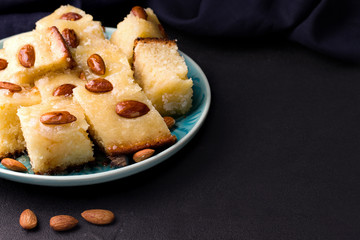 oriental dish sweet cake with semolina, coke chips and Busbus nuts on a black background. copy space