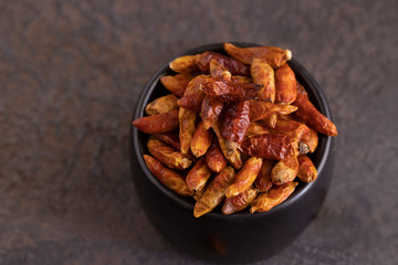 Dried chilli pepper in black bowl on concrete background. Hot and Spicy Seasoning for cooking concept.