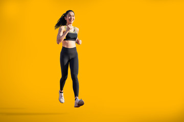 Fototapeta na wymiar asian woman running on yellow background with copy space