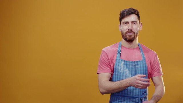 Caucasian handsome sexy chef in the kitchen shaking off flour powder on apron standing on background crossing arms feel satisfied. For advertising. Copy space.