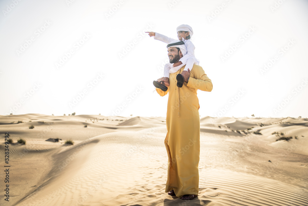 Wall mural Arabian man and son playing in the desert