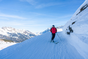 Fototapeta na wymiar A middle aged male enjoys skiing on the slopes on Mannlichen mountain in Grindelwald, Switzerland. Active lifestyle concept.