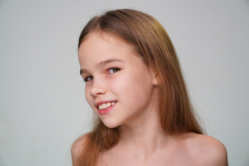 A teen girl with blond hair against a white wall