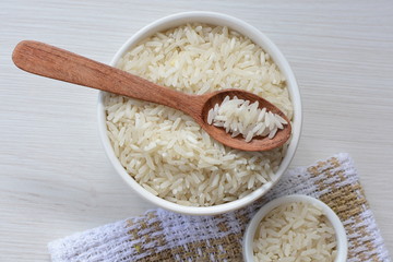 Natural raw white rice grains, on display in bowl and wooden spoon
