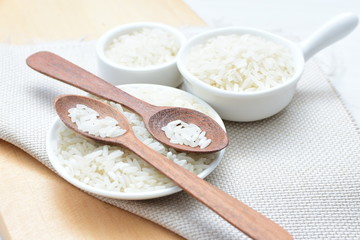 Natural raw white rice grains, on display in bowl and wooden spoon