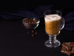 coffee with ice, caramel and cream on a black background. copy space