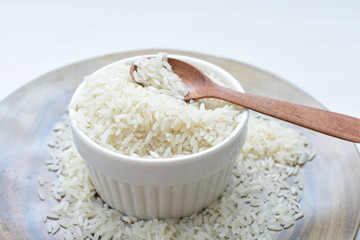 Natural raw white rice grains, on display in bowl and wooden spoon