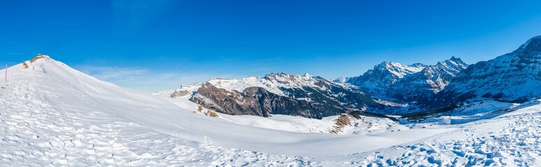 Fototapeta premium Wide parnoramic view of snow covered Swiss Alps from Mannlichen mountain in Grindelwald ski resort, Switzerland