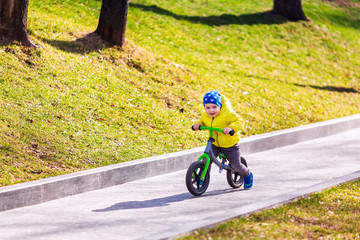 Obraz premium Happy little boy riding a run-bike in the park