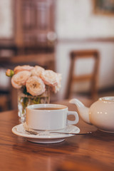 Beautiful fresh roses near a cup of tea and a in pastel tones romantic mood