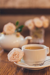 Beautiful fresh roses near a cup of tea and a in pastel tones romantic mood