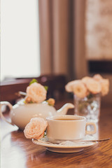 Beautiful fresh roses near a cup of tea and a in pastel tones romantic mood