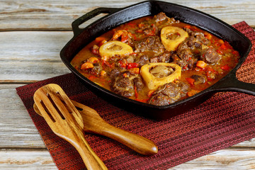 Beef shank cooked in iron skillet with vegetable.