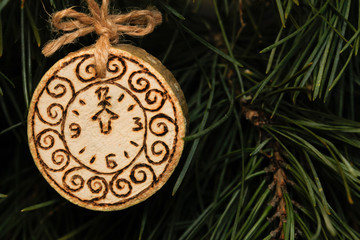 A toy on a Christmas tree made of sawn wood, a clock is burned on it.