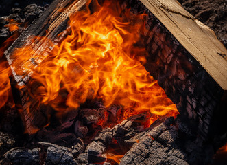 Close-up of roaring orange campfire flames licking charred logs and glowing embers, perfect cozy outdoor fire imagery for camping and warmth.