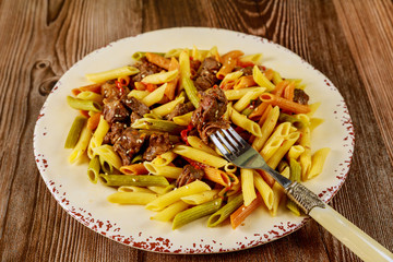Penne pasta with beef and bolognese sauce and vegetable in plate with fork.