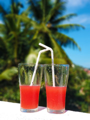 Two glass glasses with freshly squeezed juice and frangipani flower