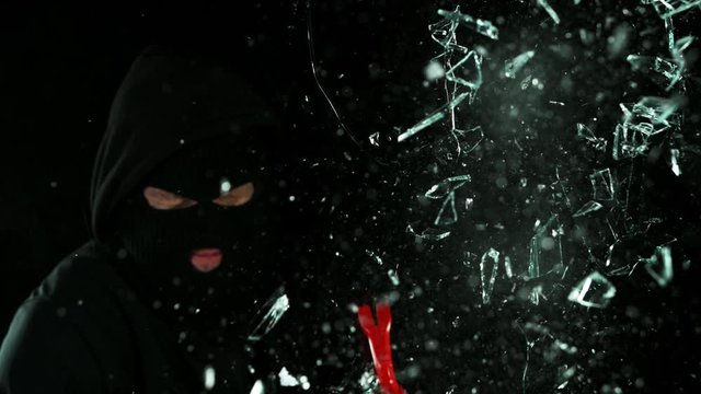 Super slow motion of burglar breaking glass on black background. Filmed on high speed cinema camera, 1000 fps.