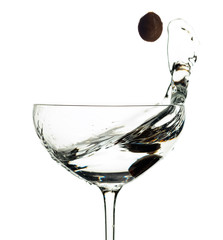 Martini and green olive in glass with splashes isolated on white .