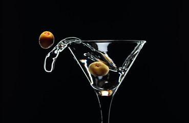 Silhouette of martini with green olives on a black background.