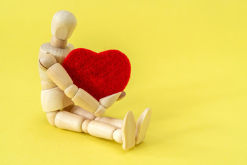 Wooden man holding a red heart