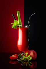 Cocktail Bloody Mary with celery on a black reflective background.