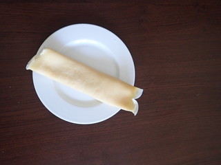   single rolled pancake on a white plate