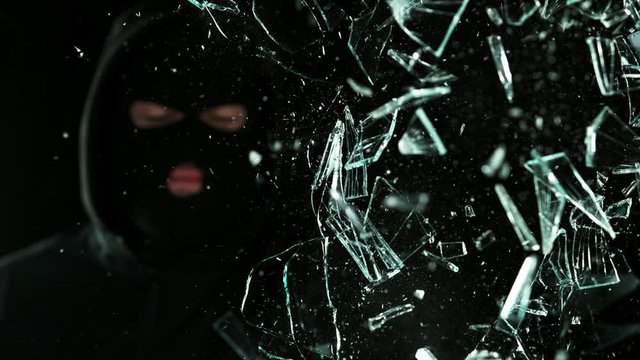 Super slow motion of burglar breaking glass on black background. Filmed on high speed cinema camera, 1000 fps.