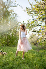 Fototapeta premium Young attractive girl walks in spring green park enjoying flowering nature