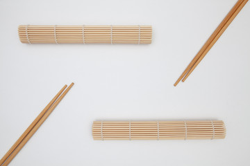 Bamboo mat with chopsticks for sushi on the white table.