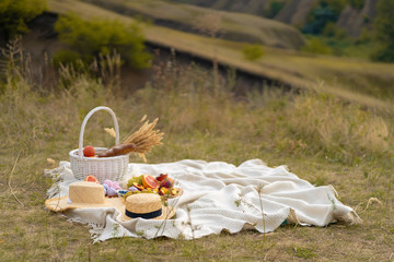 Stylish summer picnic on a white blanket. In a picturesque place the nature of the hills.