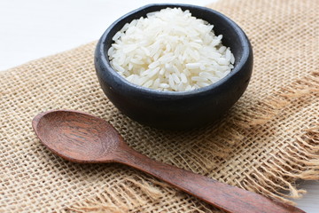 Natural raw white rice grains, on display in bowl and wooden spoon