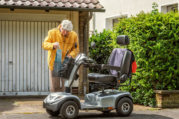 An elderly person places a bag in the transport basket of an electric vehicle - 328358155