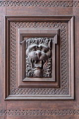 Lion head carved on wood door. Bas-relief of a lion on a door