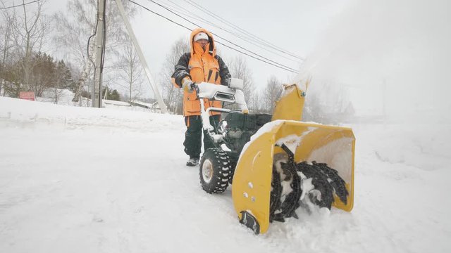 Man cleans snow with a snow thrower