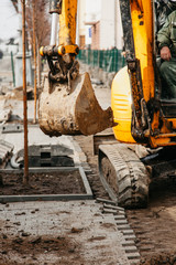 Fototapeta premium small yellow tractor with a bucket in the city
