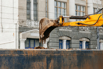 The tratkor bucket dug up the earth and loads on another car