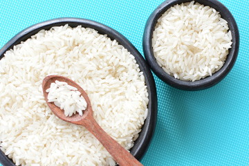 Natural raw white rice grains, on display in bowl and wooden spoon