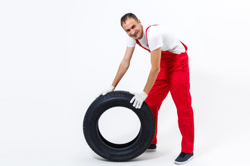 working man in full growth holds a tire on a white background