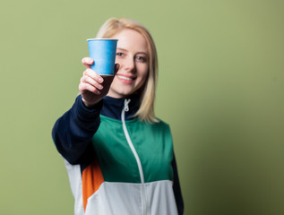 Beautiful blonde woman in 90s sport suit with paper cup