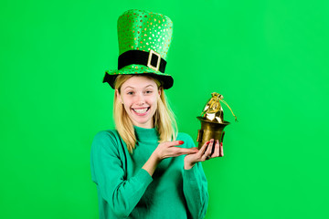 Smiling blonde girl in Leprechaun costume holds bag with gold. Green hat. Leprechaun. Bag with...