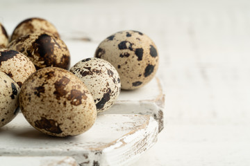 Quail eggs on a white wooden stand on a light background. Space for text, closeup