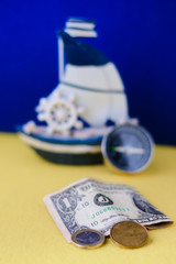 american and canadian dollar, 1 euro coin - money and travel - international money currency and a toy ship 