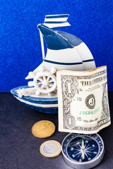 Fototapeta na wymiar american and canadian dollar, euro coin, compass and a ship on a blue background