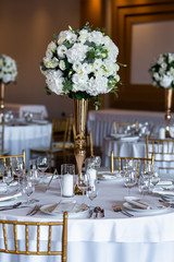 Table at a luxury wedding reception. Beautiful flowers on the table. Serving dishes, glass glasses, waiters work.