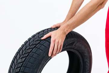 Fototapeta premium Closeup of mechanic hands pushing a black tire in the workshop.